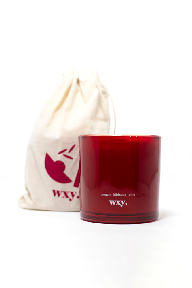 100% plant based wax candle in a red glass jar with a reusable cotton bag